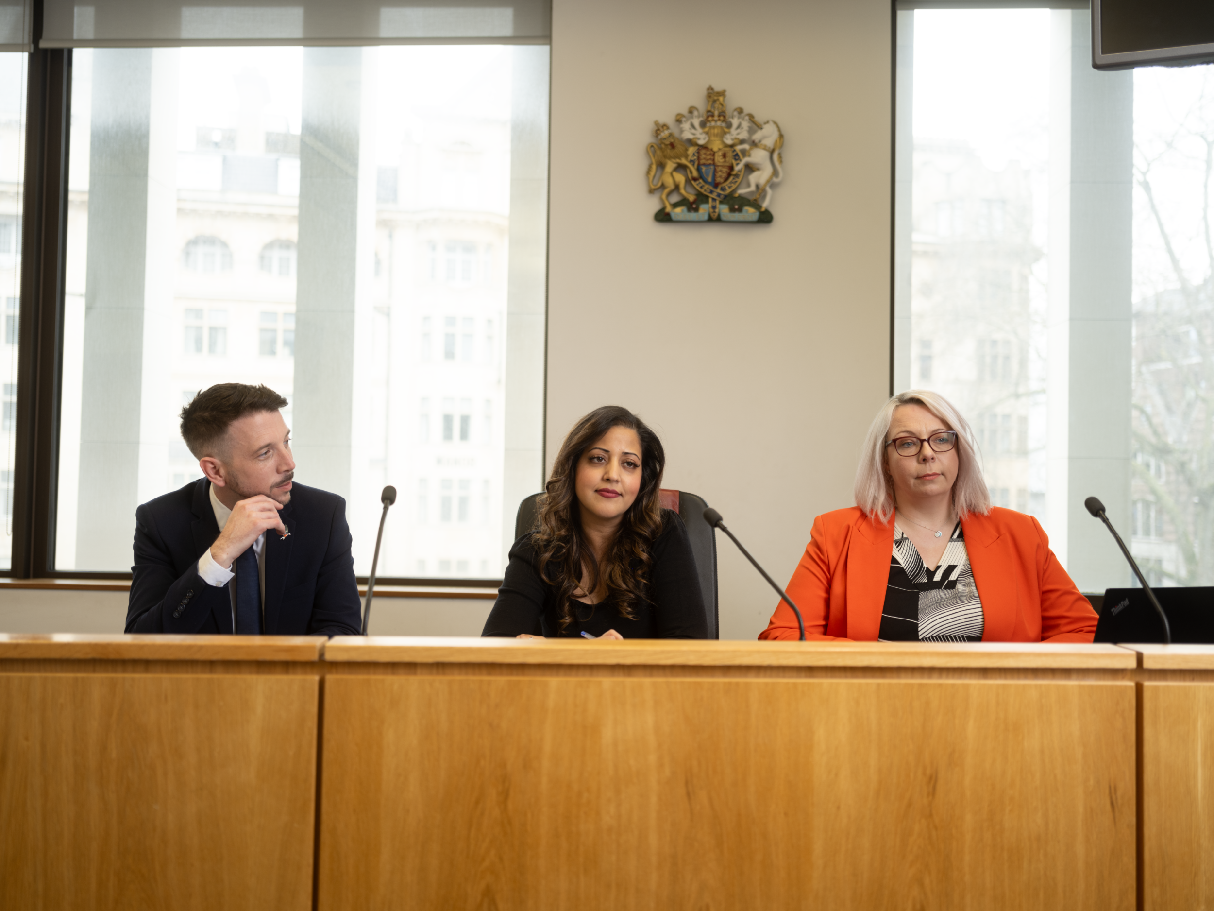 Three magistrates sitting in court on a bench. One white male, one Asian female and one white female