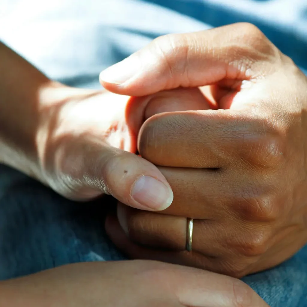 Close-up of a hand holding another hand in a supportive way