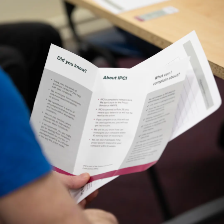 Person in prison reading an IPCI complaints leaflet.