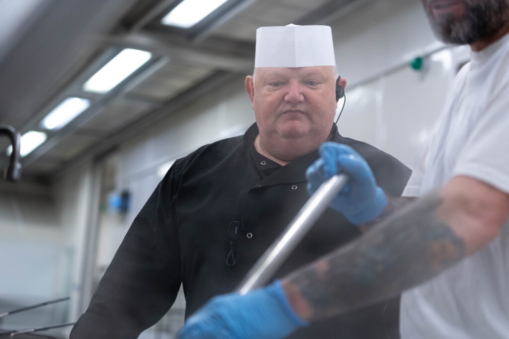 Prison caterer supervising a prisoner in a prison kitchen