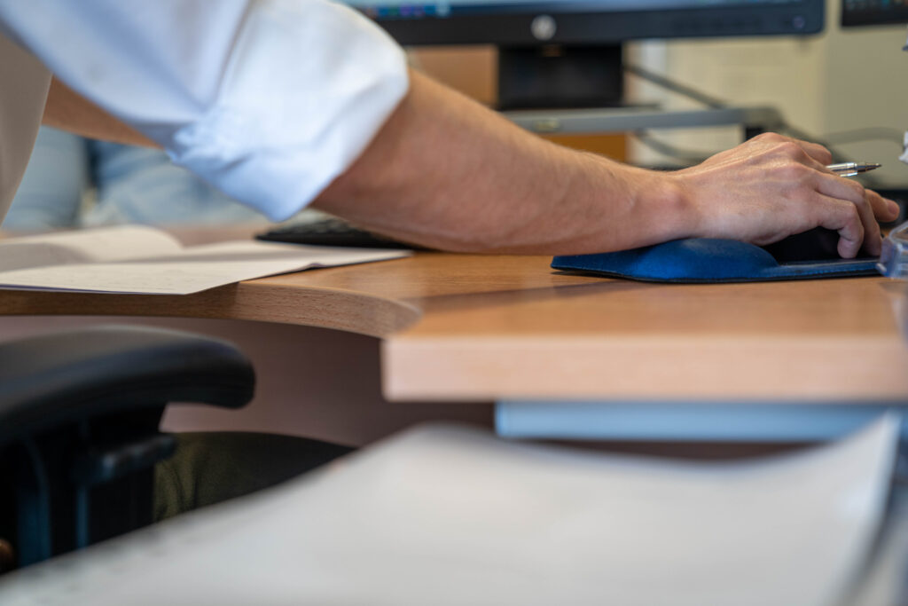 An arm of a male business administrator working at a computer desk