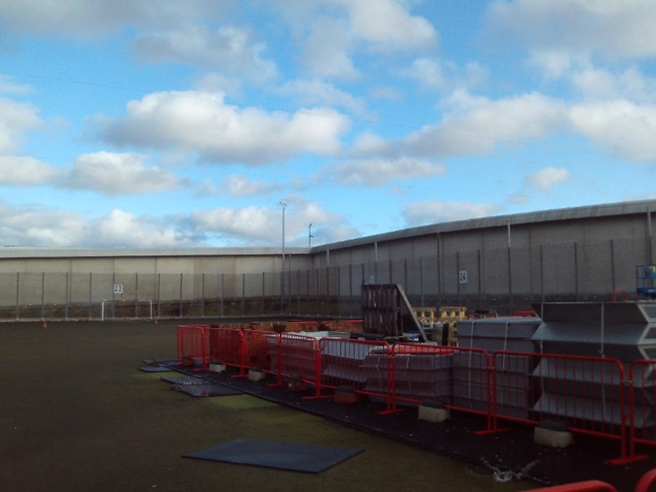 Photograph of an astroturf pitch with building materials stored on it.
