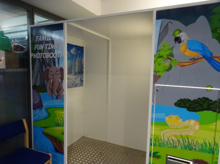 Photograph of a photo booth in the visits hall. The exterior of the booth is decorated with pictures of parrots.
