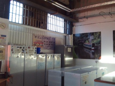 Photograph of the prison shop, with fridges arranged down wall and chest freezers in the centre of the space.
