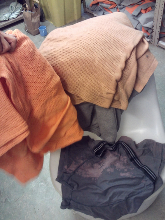 Photograph of piles of prison-issued clothing and blankets in a store cupboard.