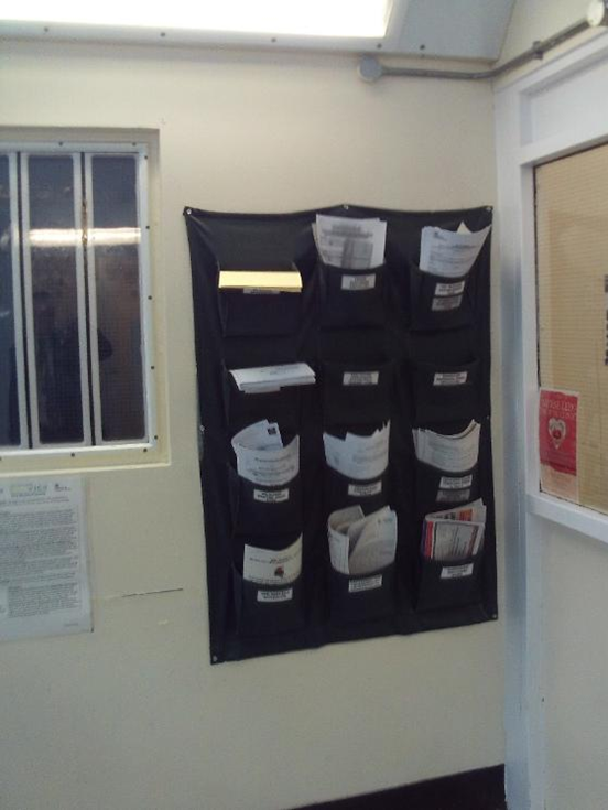 Photograph of a wall-hung document wallet with several pockets that contain paperwork that needs to be collected.