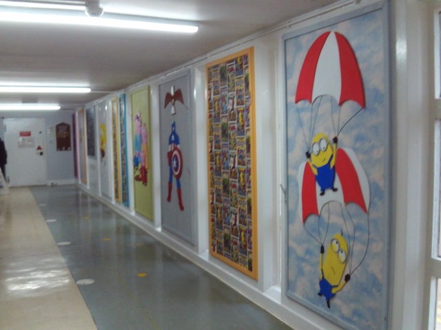 Photograph of the corridor leading to the visits area. The wal;ls are decorated with a series of bright wall murals.