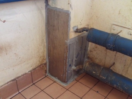 Photograph of a fix - a piece of wood that has been fixed to the wall - to stop rodents getting in through a B wing storage cupboard.