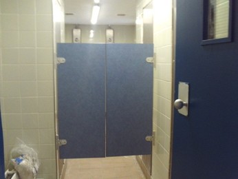 Photograph of a shower unit in which recently-installed saloon doors are visible. The doors are blue, matching another door that can be seen in the wall to the right.