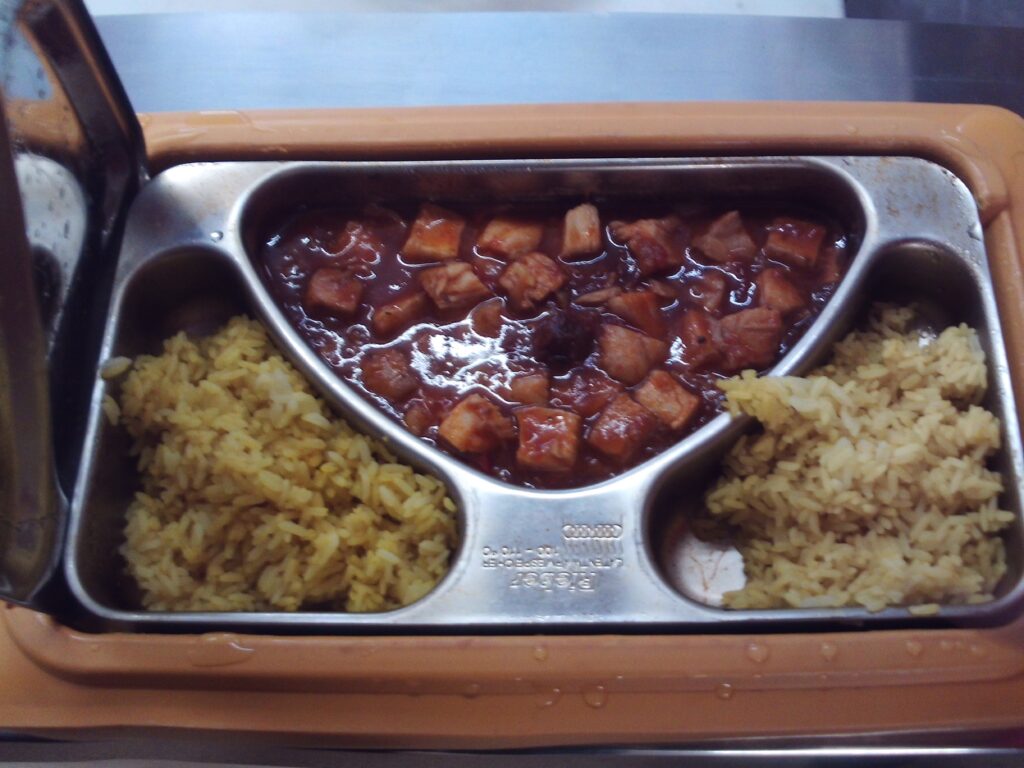 Photograph of a meal served in a Ramadan box. The box is divided into three compartments, each with a different food in it.