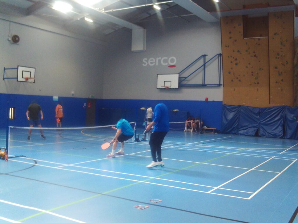 Photograph of the gym with prisoners playing tennis.