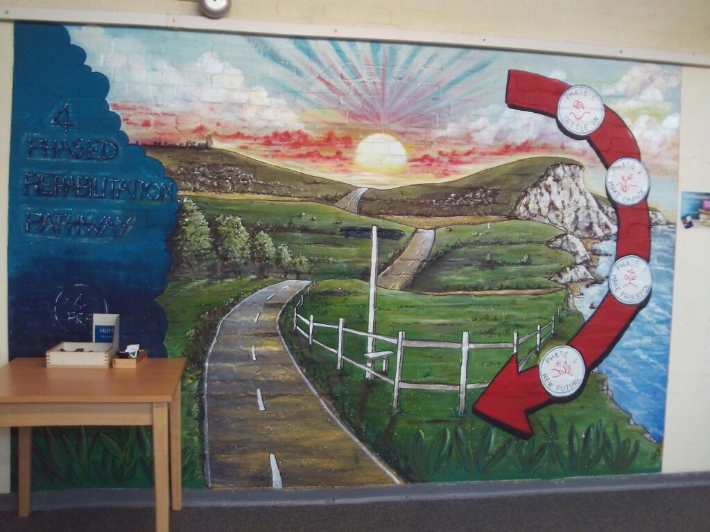 Photograph of a large mural in the resettlement hub. It depicts a road stretching into a landscape with a sun hovering above the horizon.