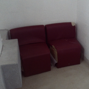 Photograph showing damaged furniture in reception. There are two comfortable chairs with rips in the fabric.