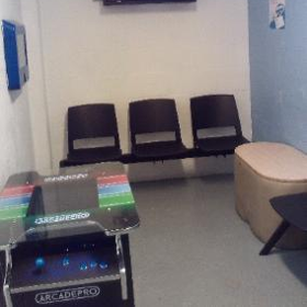 Photograph of an arcade machine in the holding room. There are also some chairs and a small coffee table.