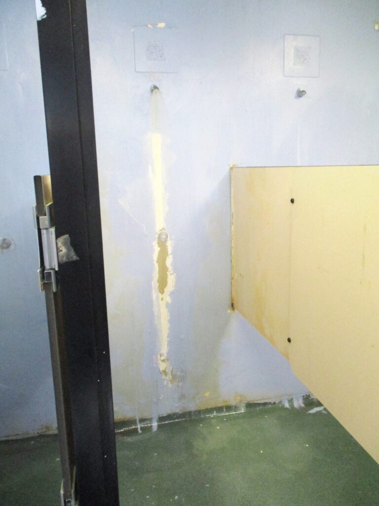 Photograph of communal showers, showing some wear and tear.