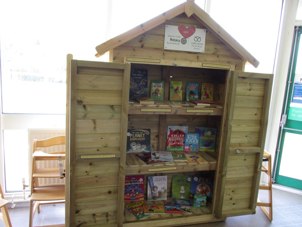 Photograph of a small bookshelf rendered in the form a shed, stocked with children's books.