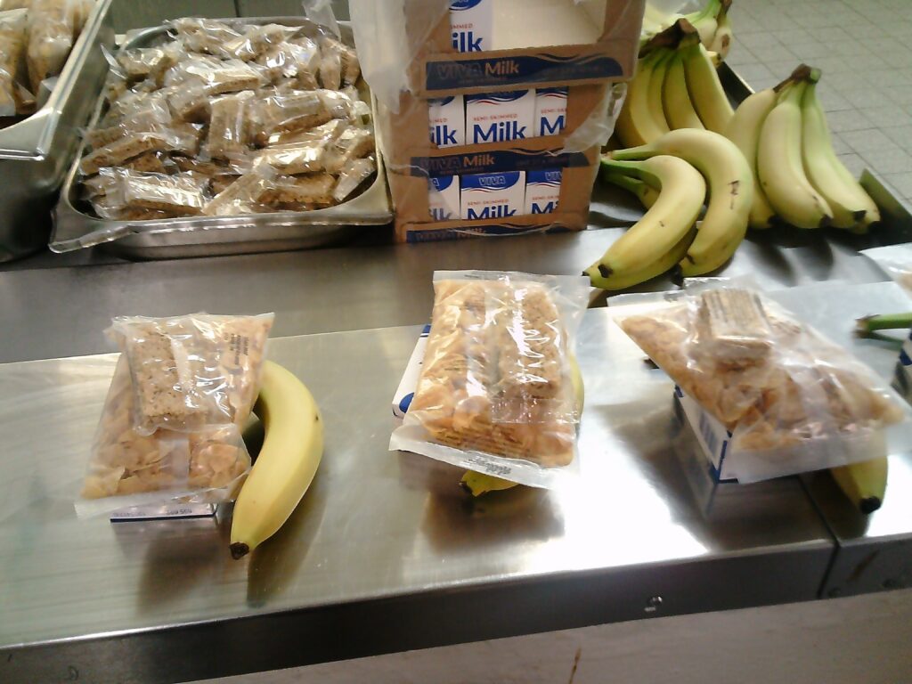 Photograph of breakfast food prepared in packs awaiting collection.