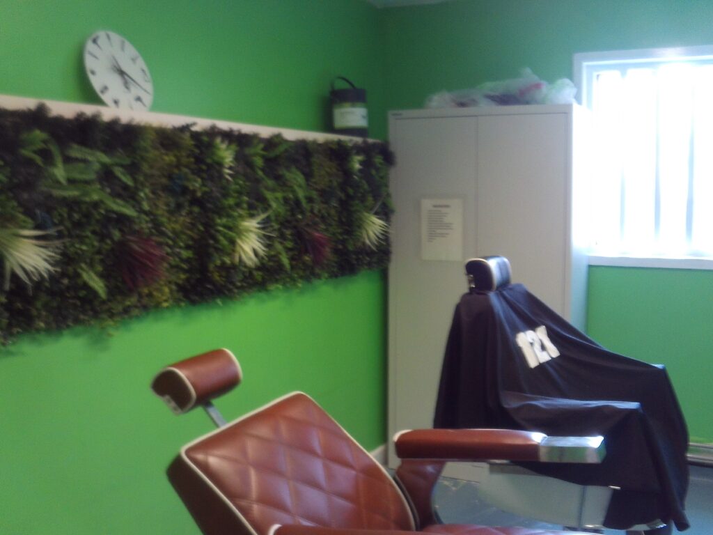 Photograph of the ISFL barber shop. Two chairs can be seen, one with a cape draped over it.