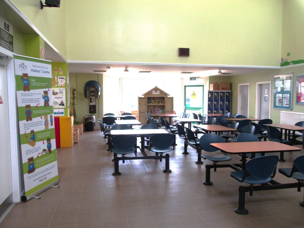 Photograph of the inside of the visitors' centre, with a number of tables with chairs around them lined up in rows.