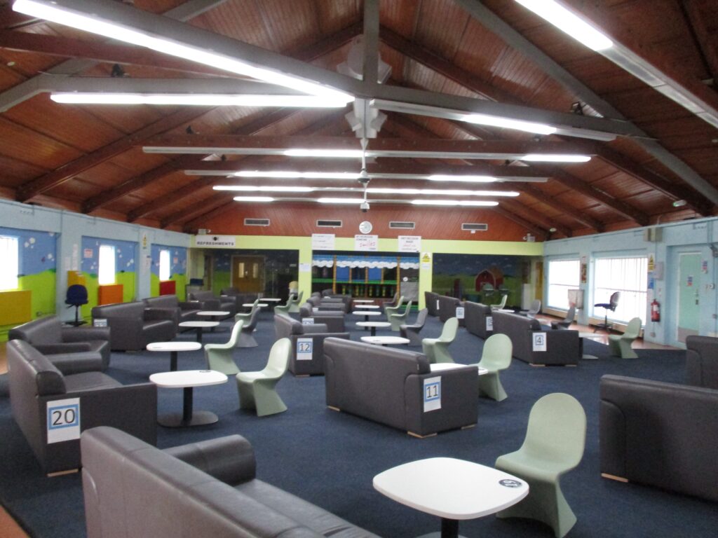 Photograph of the interior of the visits hall, with easy chairs arranged coffee tables.