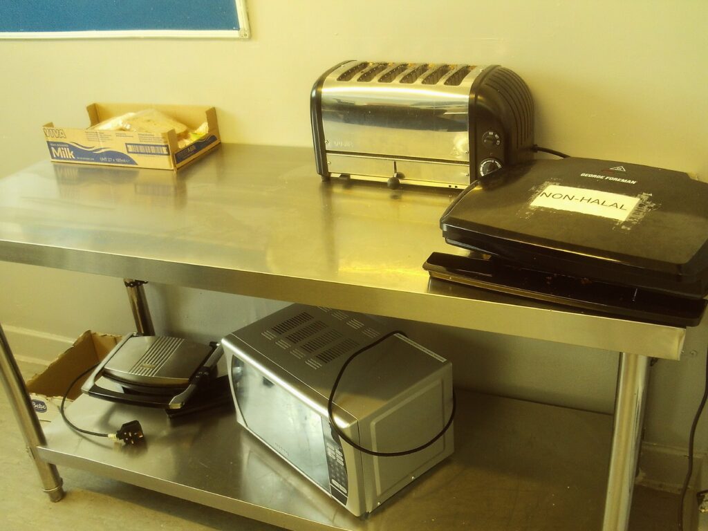 A photograph of self-catering equipment on a residential unit. A stainless stell unit has a microwave, toaster and other equipment on it.