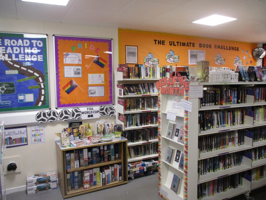 Photograph of the main library. Several well-stocked bookshelves can be seen and there are information displays and posters on the walls.