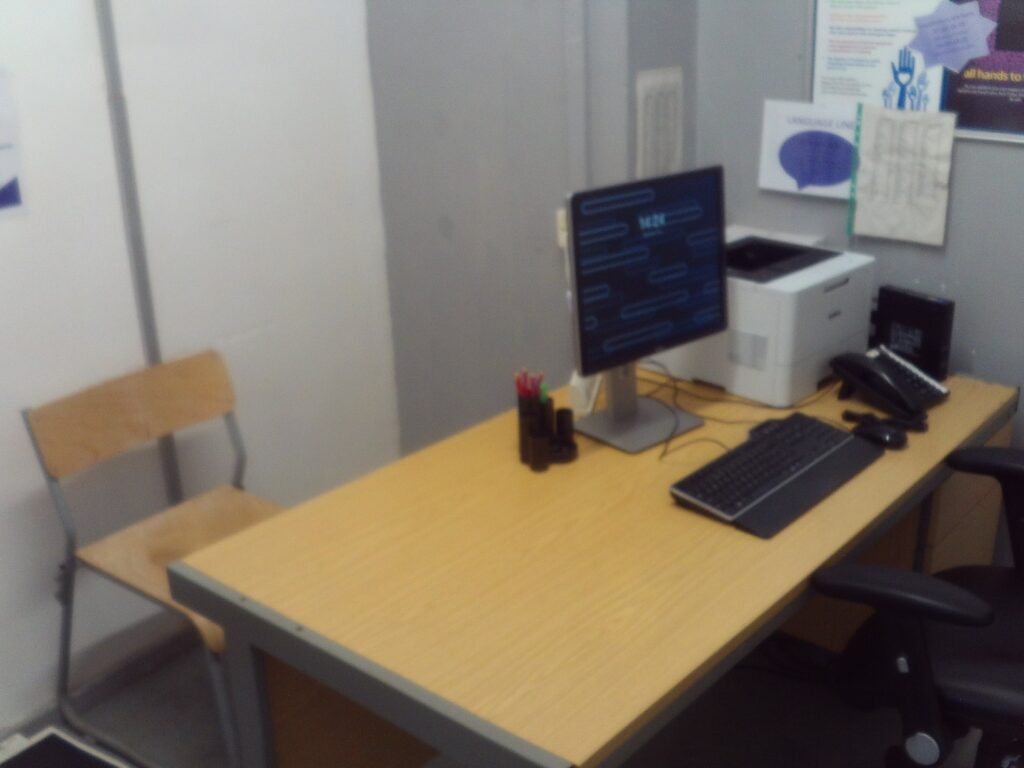 Photograph of a desk on which there is a PC and printer in the health room in reception.