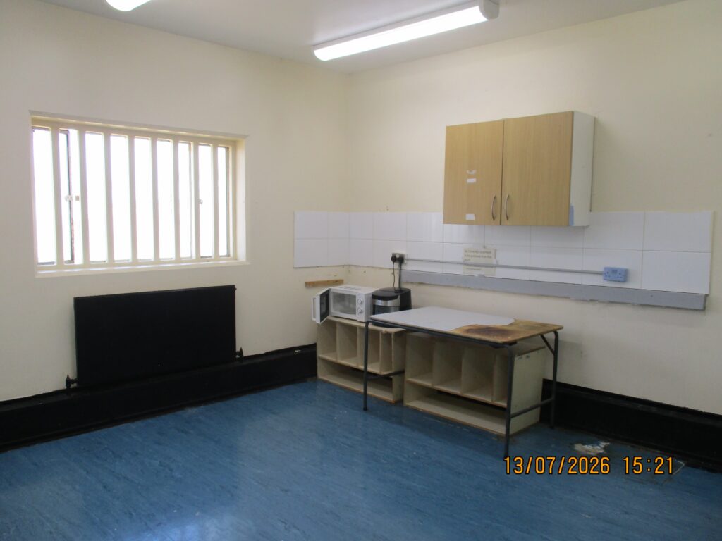 Photograph of a self-cook room on unit 4. A kitchen cabinet is positioned against one wall and there is basic cooking equipment on it.