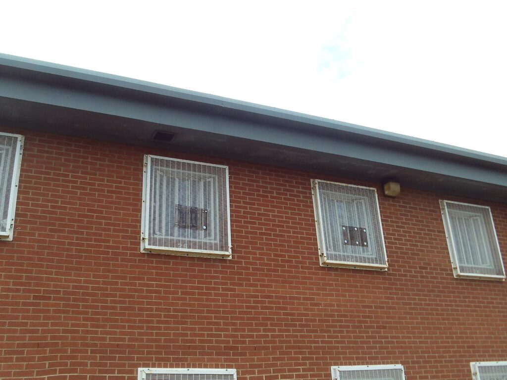 A photograph of repaired window grilles viewed from the outside of a cell block.