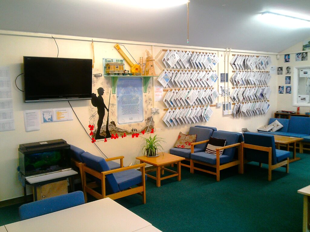 Photograph of the 'Lobster Pot' information room. Low chairs and coffee tables are arranged along one wall and there are displays of information and decorative posters on the walls.