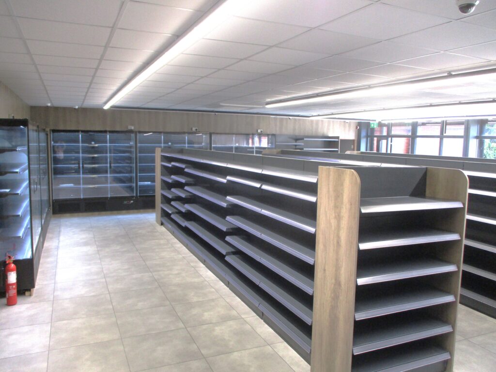 Photograph of the new prison shop, with shelves and fridges empty read to be stocked.