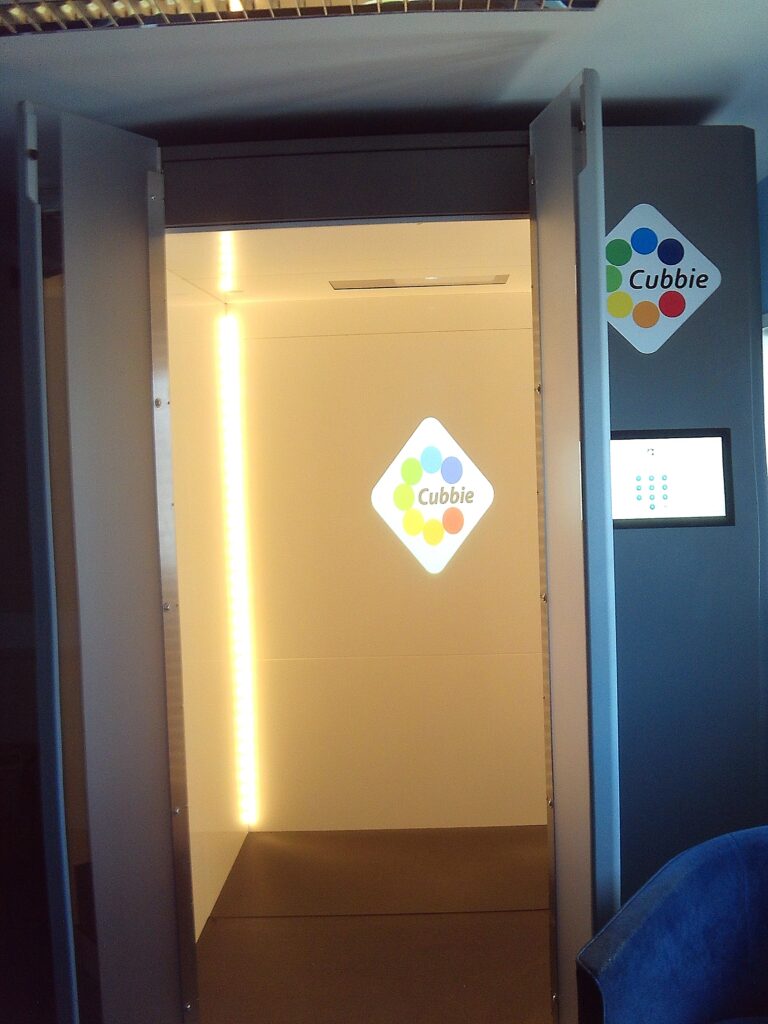Photograph of a neurodiversity sensory pod. Looking in through an open door, the pod is bathed in a dim light and has plain walls.