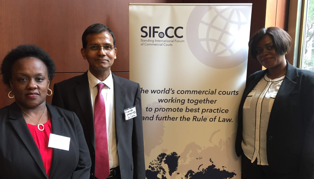 Justice Bitature, Justice Samayawardhena and Justice Alami stood next to a SIFoCC stand, that reads ‘the worlds commercial courts working together to promote best practice and further the Rule of Law