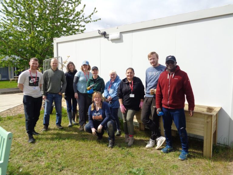 Image of gardening volunteers in a line, posing for a photo at HMP Send