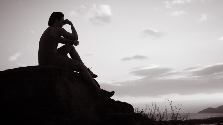 Silhouette of a person sat alone on a mound