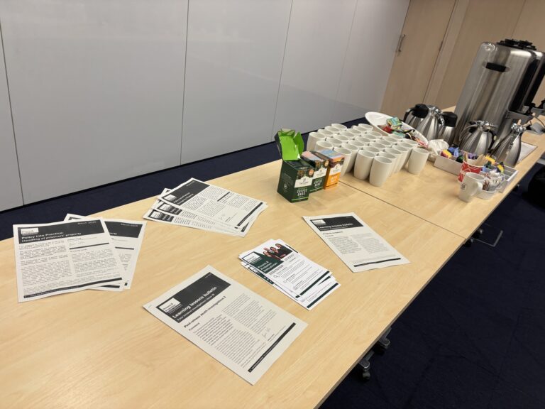 Photo of a desk with forms, peans and refreshments on it