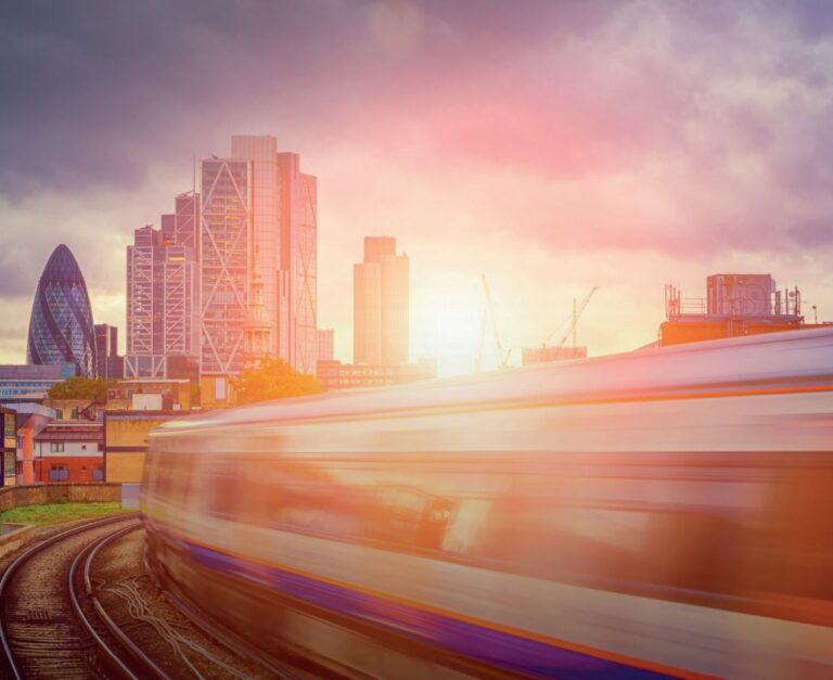 a photo of a blurred train moving quickly towards the tall office buildings in the city of London