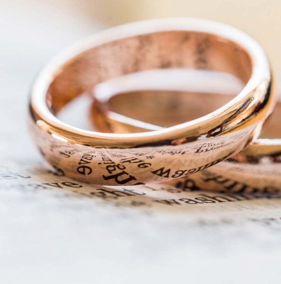 A photo of two golden rings balancing on some paper.