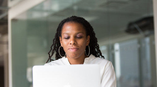 Lady in a white shirt using a laptop.