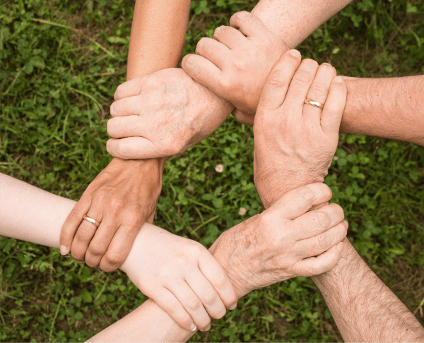 An image of 5 different hands holding on to the wrist of the hand to the side of them, forming a star.